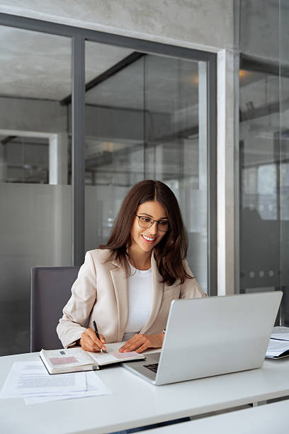 istock Vertical portrait latin hispanic woman using laptop computer for business studying having videocall with online virtual webinar training meeting, writing notes. Focused businesswoman working in office 2206586979