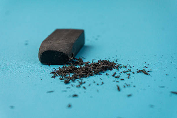 istock A dark gray eraser and its debris are displayed on a clean, smooth, turquoise background. 2206588751