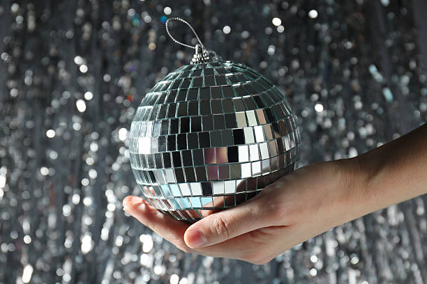istock Disco ball in hand with festive silver ribbons on background 2206595310