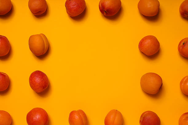 Fresh juicy apricots on a yellow background