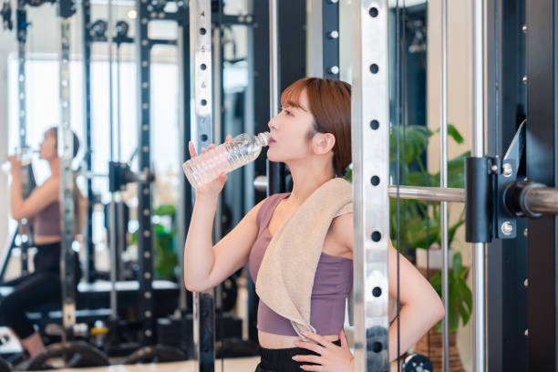 young woman hydrating at the gym - フィットネスジム ストックフォトと画像