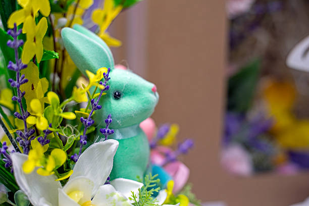 holding a cute blue Easter bunny in decorative flowers. Easter holiday