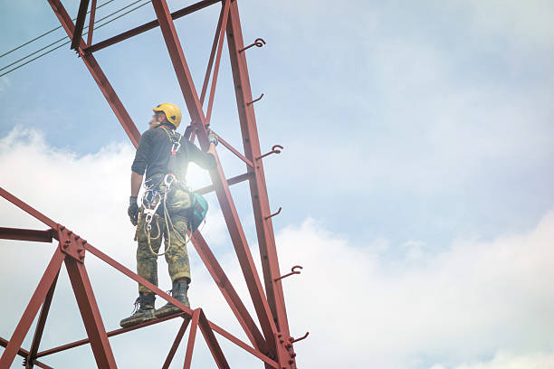 Workers install new power transmission lines and poles in Red Rocks Park and Amphitheater in Morrison Colorado on June 10, 2024 with nearby red rocks, pine forests of the Rocky Mountain Front Range in the background.