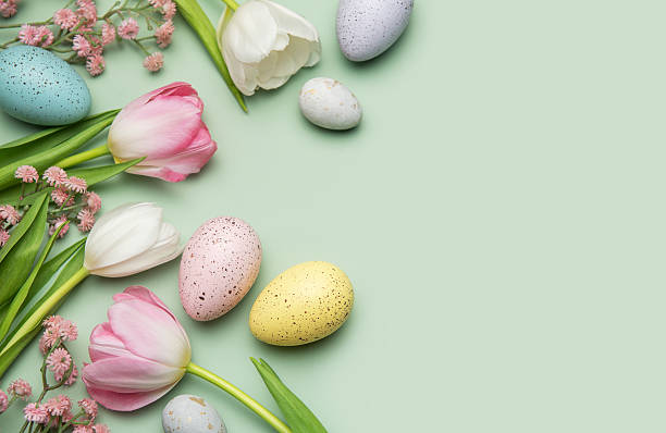 istock Easter eggs and tulips creating a border on pastel green background 2206610998