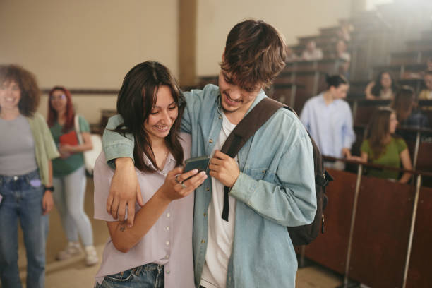 istock Happy university couple in love using cell phone in lecture hall. 2206615931