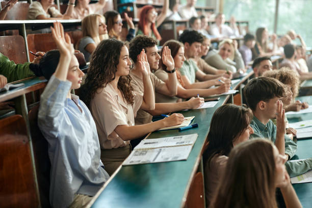 istock College students raising their hands on a class at lecture hall. 2206616218