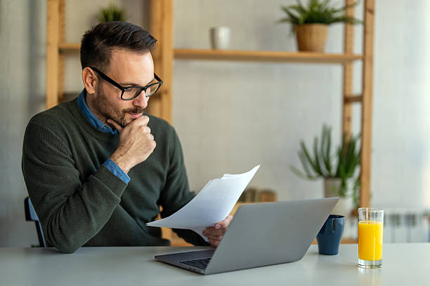 istock Business man accountant analyst holding documents, work at laptop computer doing online trade market 2206616718