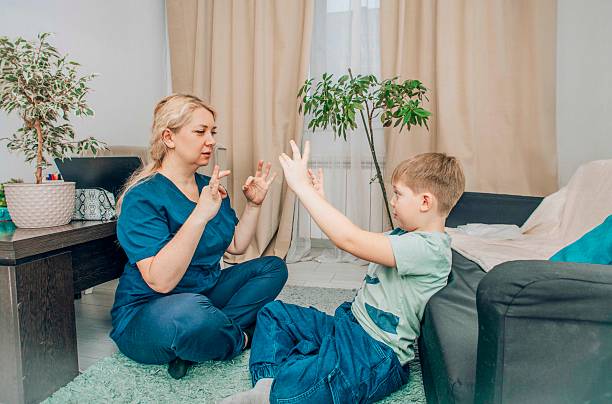 istock female therapist and boy practicing hand gestures in therapy session, cozy home setting, concept of child development and alternative communication 2206618241