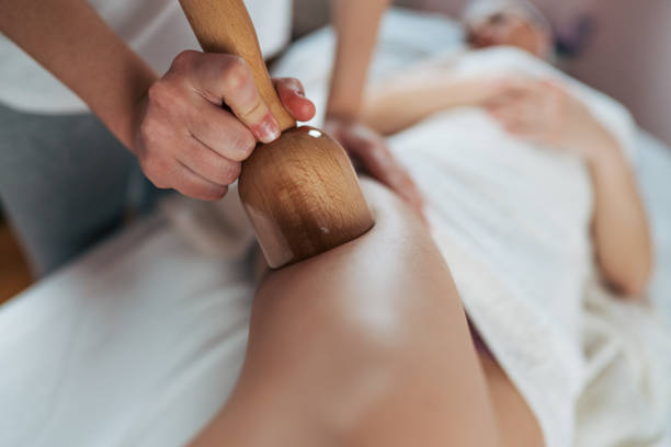 istock Masseuse using wooden tool massaging leg of client 2206619362