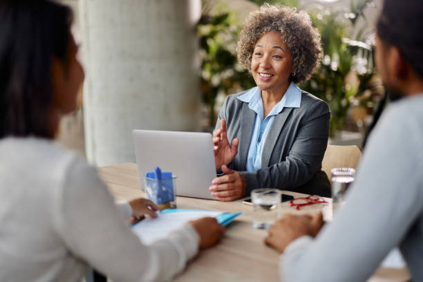 istock Happy female agent using laptop and talking to her customers in the office. 2206619491