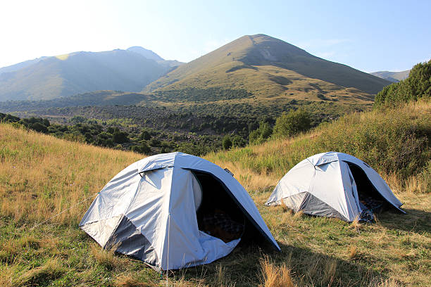 Merki, Kazakhstan - August 15, 2024: People camping in nature. Camping site in a mountainous area. Single tents located in the campsite. Portable tents on the lake shore.