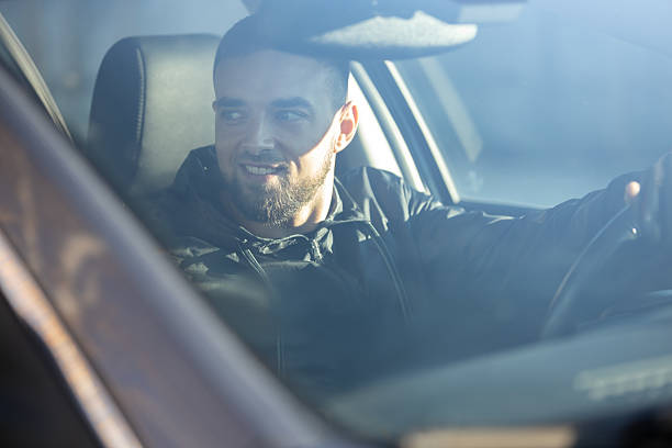 istock A smiled handsome man sits behind the wheel, driving a car 2206620083