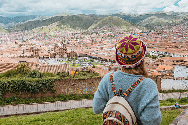 Young traveler in colorful hat overlooking scenic cityscape. Woman enjoying vacation with a beautiful urban backdrop. Tourist exploring cultural landscape from a hilltop.