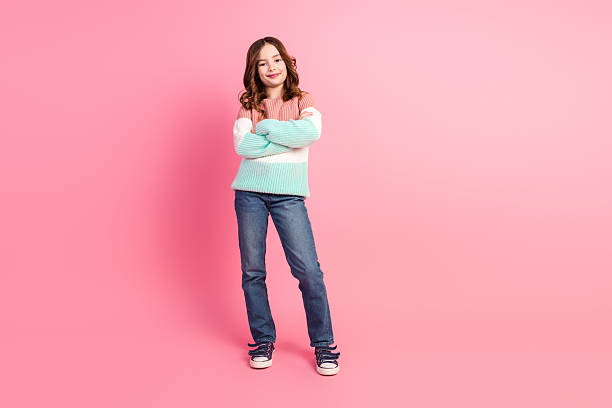 istock Stylish girl in casual pullover posing confidently against a pink background, showcasing trendy fashion with a cute and happy expression. 2206623397