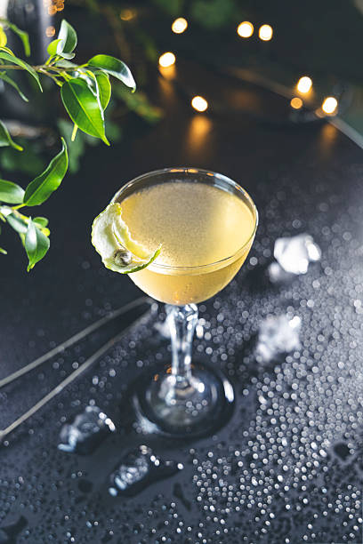 istock Refreshing yellow cocktail garnished with lime peel on wet bar top 2206624091