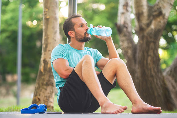 istock Young sportsman taking break and drinking water from bottle in park 2206624462