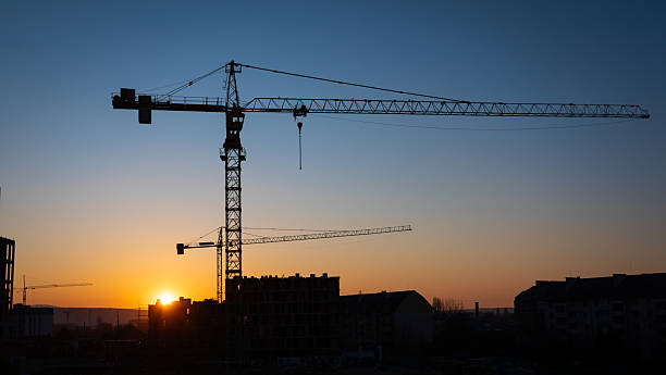 istock Construction cranes silhouetted against a vibrant sunset sky on a clear evening 2206628465
