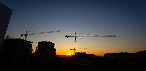 istock Sunset over construction site with cranes silhouetted against evening sky 2206628486