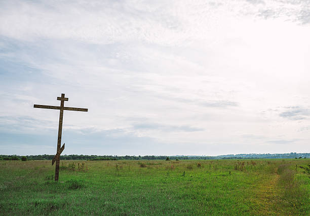 istock Orthodox cross stands alone in a quiet green field. 2206629744