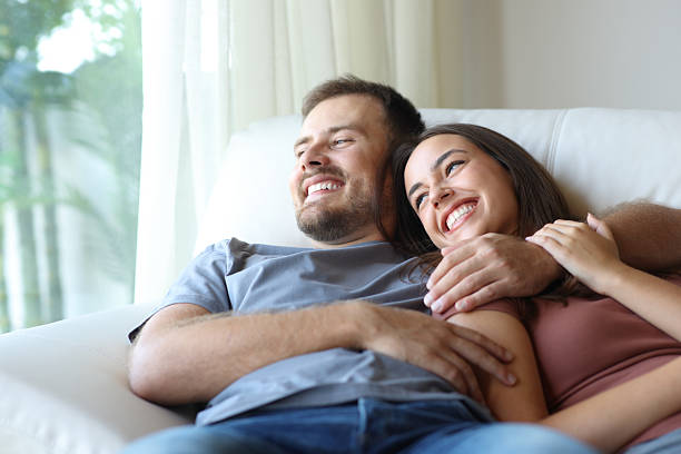 istock Happy couple at home relaxing on a couch looking away 2206630121