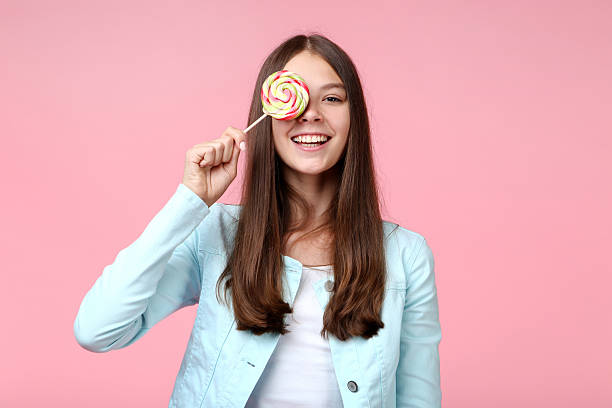 istock Young girl with lollipop on pink background 2206633292