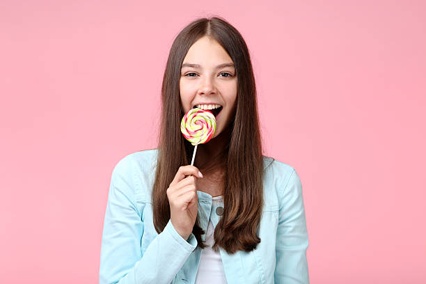 istock Young girl with lollipop on pink background 2206636285