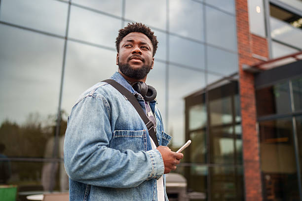 istock Young Black Man Using Smartphone with a Positive Expression on the Street 2206636347