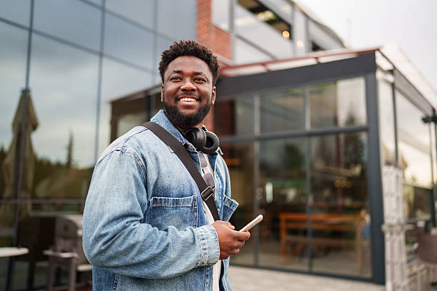 Young Black Man Using Smartphone with a Positive Expression on the Street