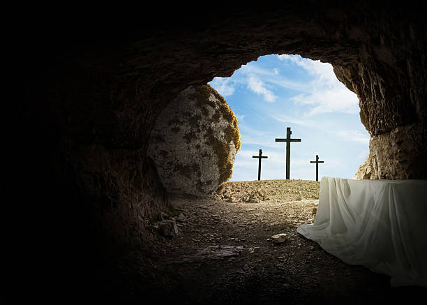 Easter and Good Friday concept, empty tomb with cross on mountain on a blue sky. Creative idea Easter. Religion and Christianity. Open empty cave. Free copy space for design