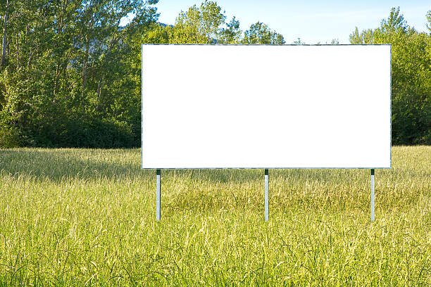 istock Blank advertising signboard in a green field with trees on background - concept with copy space 2206637876
