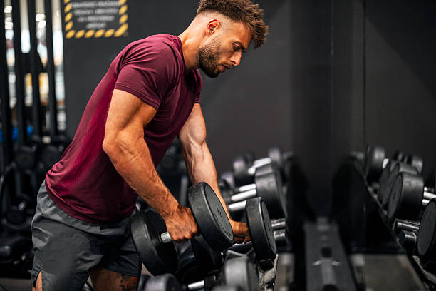 istock Young Athletic Man Lifting Dumbbells in Modern Gym Setting 2206638313