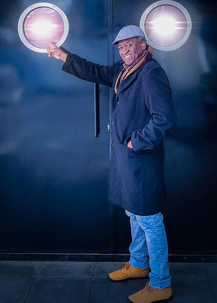 Fashionable senior man points at a bright circular window on a modern building