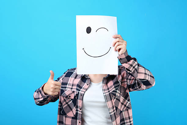 istock Girl holding paper with drawing face on blue background 2206644745