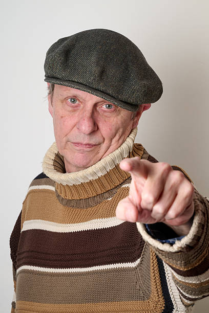 Portrait of bearded adult man in classic plaid flat cap, turtleneck and eyeglasses isolated on grey