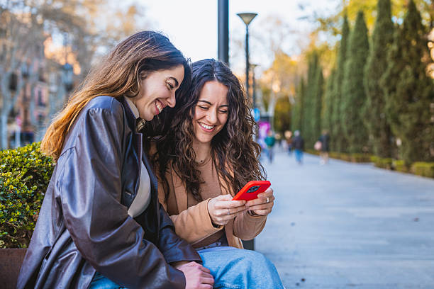 istock Two Happy Women Looking at Smartphone in Park 2206648205