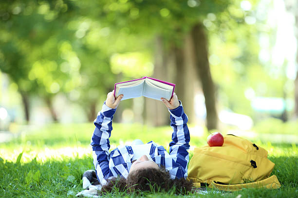 istock Young girl with book lying in the park 2206649143