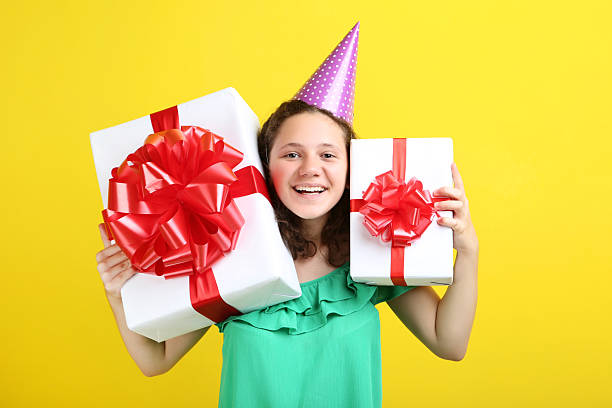 istock Beautiful young girl with gift boxes on yellow background 2206649537