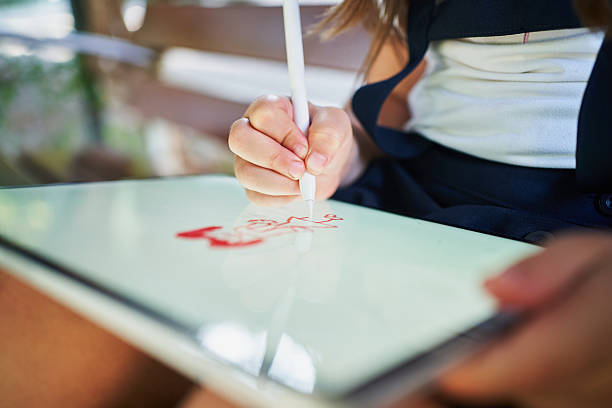 Elementary school student drawing on tablet with stylus pen outdoors