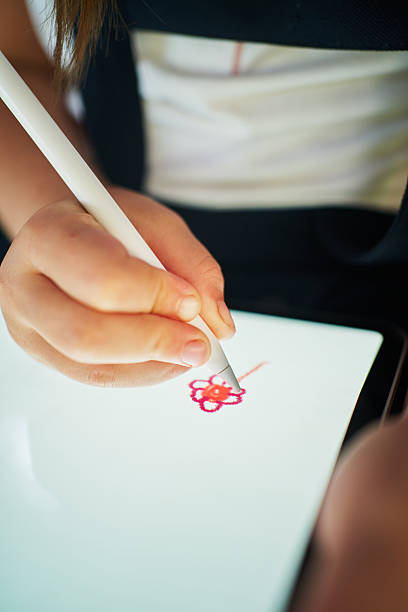 istock Schoolgirl drawing flower on tablet with stylus 2206654436