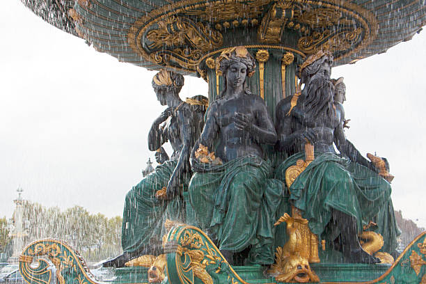 Paris, France - October 15, 2025,The Fountain of the Seas in the Place de la Concorde is notable for its highly detailed mythological sculptures, featuring female figures surrounded by gilded ornaments and marine motifs. The gray sky adds drama to the scene, while the green and gold tones reinforce the ornamental and symbolic character of the ensemble. Ideal for tourism, editorial, and cultural content about public art, urban heritage, and classical mythology in Paris