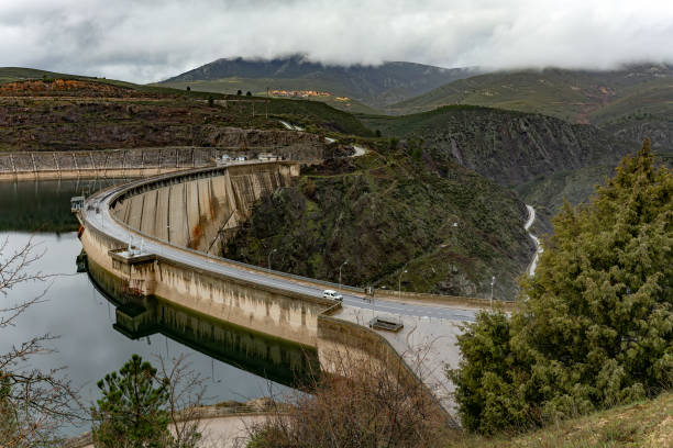istock Curved dam reflecting in reservoir water under cloudy sky 2206658206