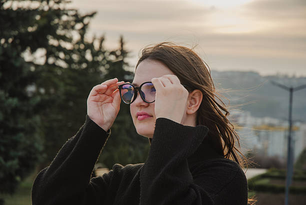 istock Young woman adjusting glasses outdoors at sunset. Glasses for vision 2206658581