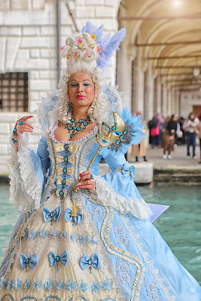 Venice. Italy. 1st of March 2025.Beautiful costumed person stading in Venice near the Bridge of Sighs - & the Doge Palace.  The Carnival is an annual public event - where people travel from all over to participate, photograph or just enjoy the beauty.