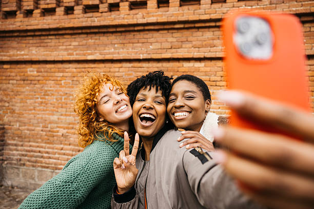 istock Three happy women taking a selfie in front of a brick wall 2206666742