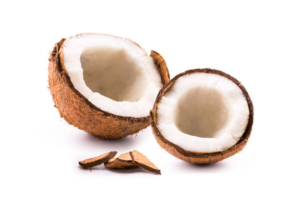Fresh coconut is split open to reveal the creamy white flesh inside, surrounded by its textured brown shell. The bright setting emphasizes the natural colors, highlighting the freshness and inviting nature of the fruit.