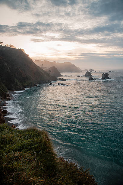 istock Dramatic coastal cliffs and rocky shoreline at Playa del Silencio, Asturias, Spain, during serene sunset with misty hills and moody sky over the Atlantic Ocean 2206667376