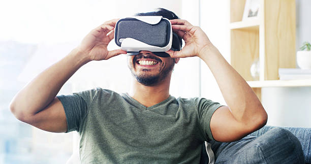 istock Gamer, virtual reality and smile with man on sofa for metaverse, 3D experience and cyber. VR headset, video games and simulation with person in living room at home for entertainment and futuristic 2206672121