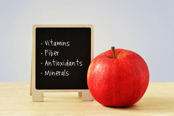 Red apple with some of its healthy nutritional components written on blackboard