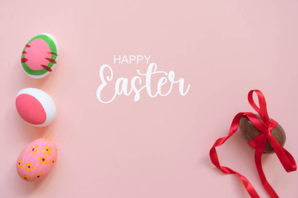 Sweet chocolate egg with bow and painted easter eggs on pink background, top view. Space for text