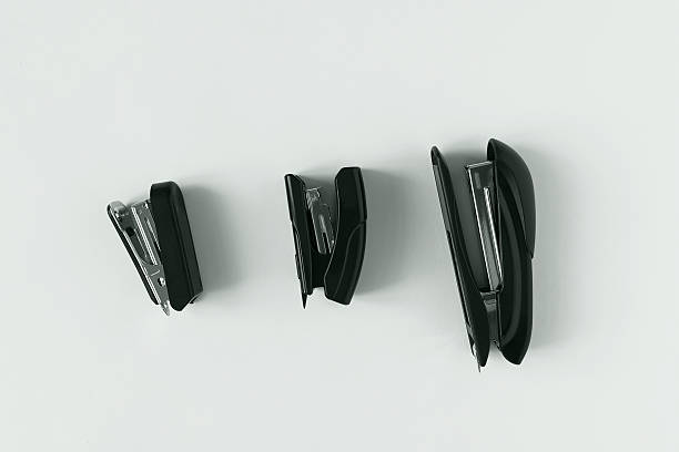 close up of a green mini stapler with shiny metal elements placed on a white paper base